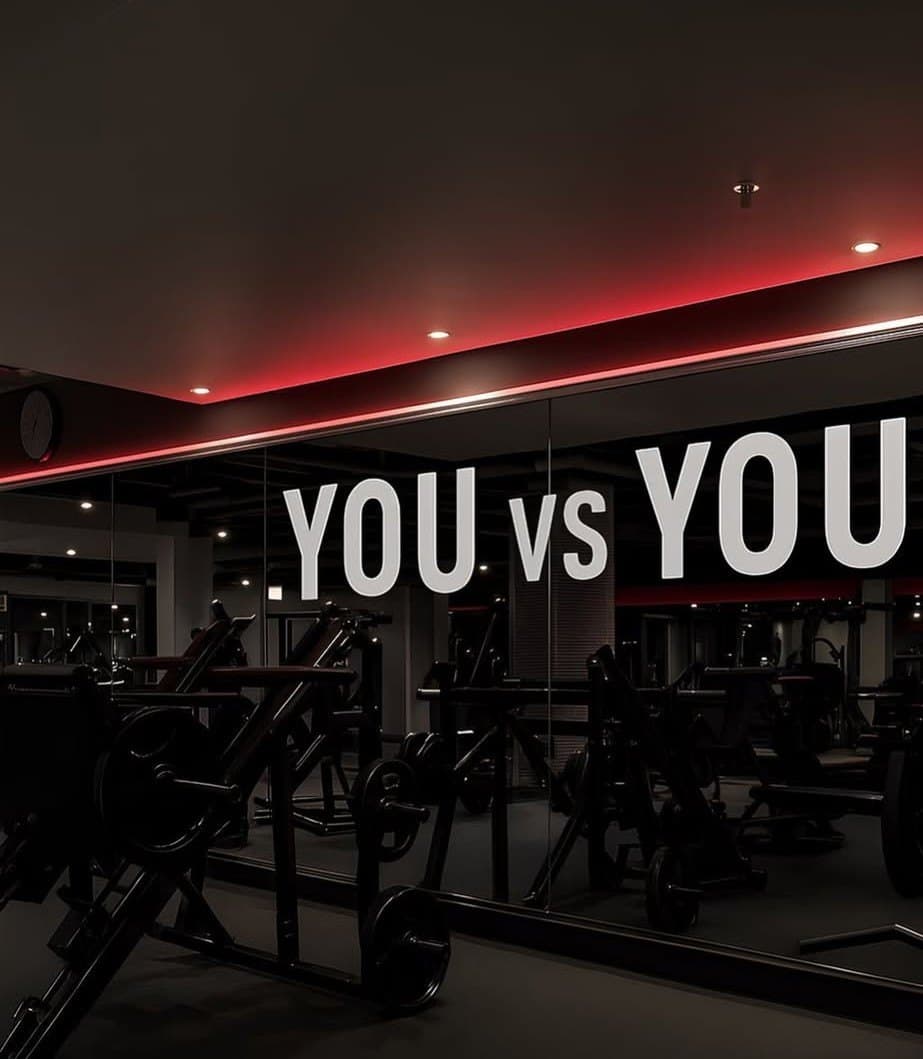 A dark gym with the words YOU vs YOU across the mirror